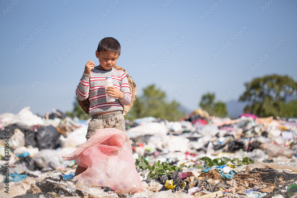 Poor boy collecting garbage in his sack to earn his livelihood, The concept  of poor children and poverty Stock Photo