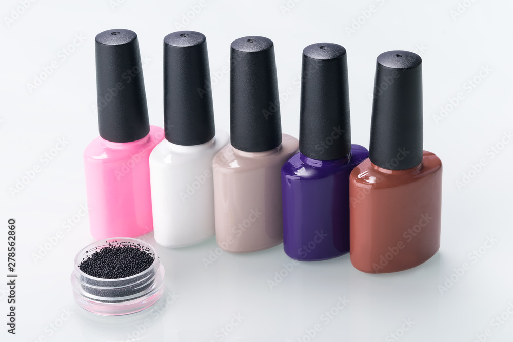 multi-colored nail polishes are in a row on a light background multi-colored nail polishes are in a row on a light background
