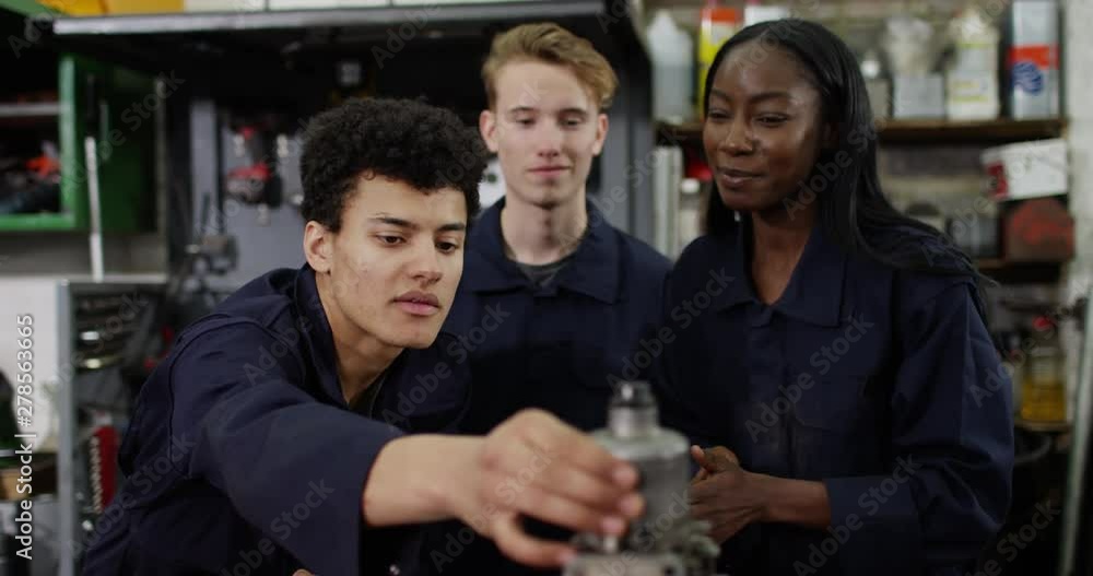 4K Female mechanics teacher explaining to students in workshop. Slow motion. 4K Female mechanics teacher explaining to students in workshop. Slow motion.