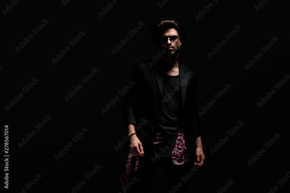 Mysterious young man wearing sunglasses, a black hat and jacket Mysterious young man wearing sunglasses, a black hat and jacket