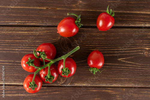 Group of eight whole fresh red tomato cherry flatlay on brown wood