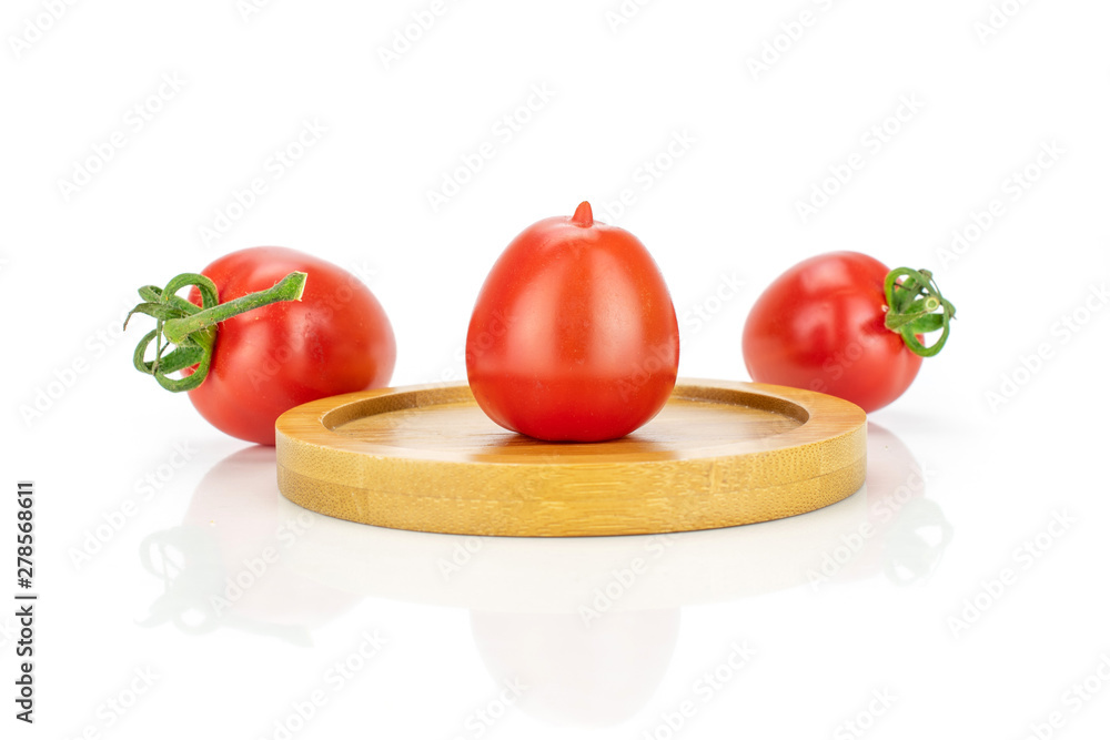 Group of three whole fresh red tomato cherry one on a bamboo plate isolated on white background Group of three whole fresh red tomato cherry one on a bamboo plate isolated on white background