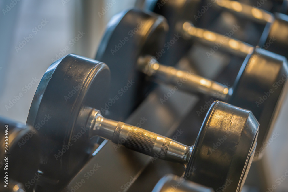 Black dumbbell set. Close up many metal dumbbells on rack in sport fitness center , Weight Training Equipment concept. Black dumbbell set. Close up many metal dumbbells on rack in sport fitness center , Weight Training Equipment concept.