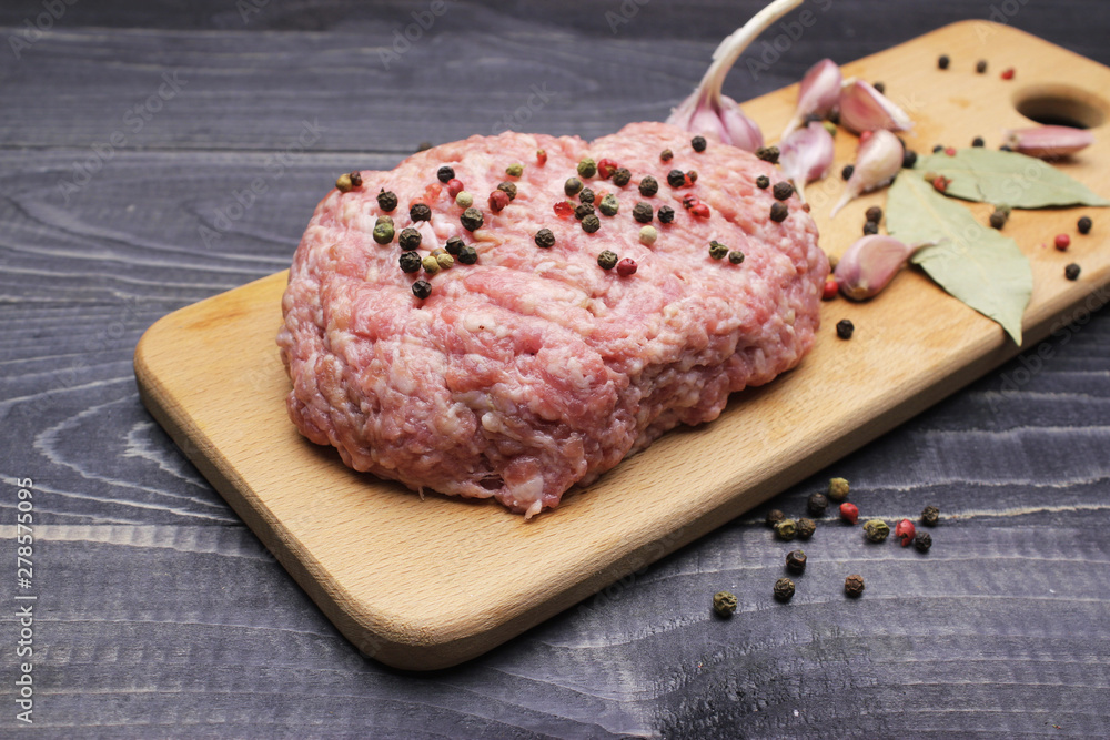 Burger. raw minced meat on cutting board with farlic and cpices onblack table top Burger. raw minced meat on cutting board with farlic and cpices onblack table top