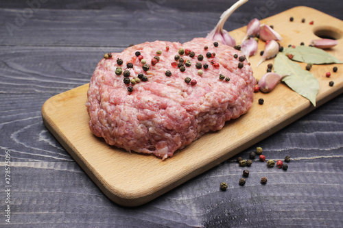 Burger. raw minced meat on cutting board with farlic and cpices onblack table top photo
