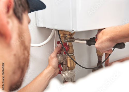 Obraz na plátne The man is installing the heater system in the house and checking pipes by the w