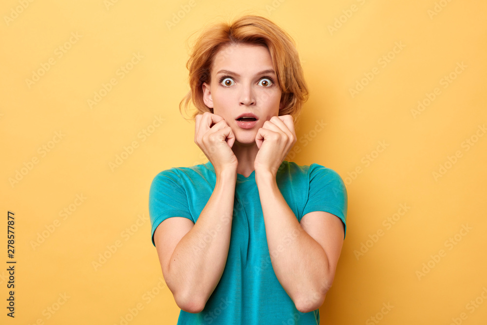 fair-haired girl in blue T-shirt expresses shocked emotion, cannot believe in something, fobia, fear concept fair-haired girl in blue T-shirt expresses shocked emotion, cannot believe in something, fobia, fear concept