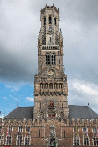 Bruges, Flanders, Belgium -  June 15, 2019: Frontal view on the brown stone Halletoren building, named Belfort or Belfry, against gray cloudscape. photo