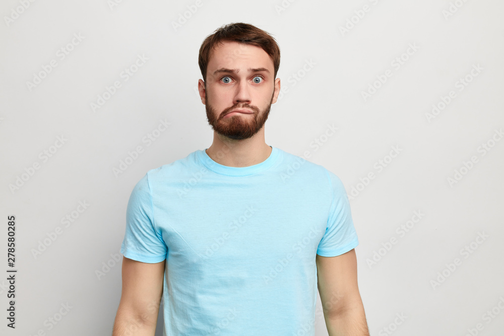 Fototapeta premium young funny man in stylish T-shirt isolated on blue background, studio shot. facial expression . emotion and feeling