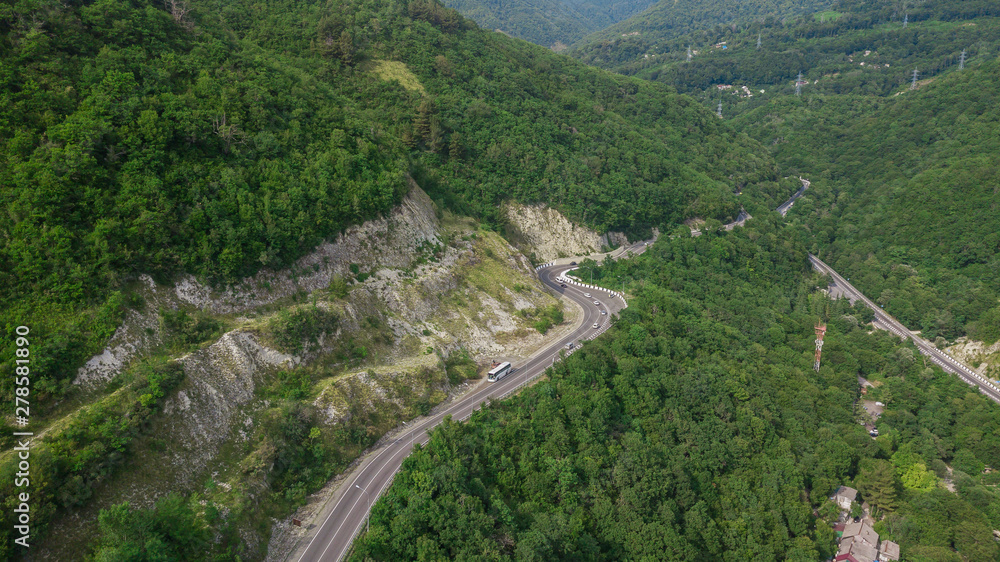 Drones Eye View - winding road from the high mountain pass in Sochi, Russia. Great road trip trough the dense woods.