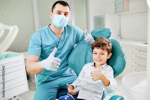 Happy dentist and child raised their thumb