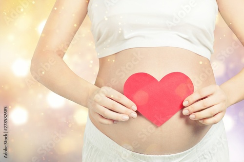 Close up of a cute pregnant belly and red heart