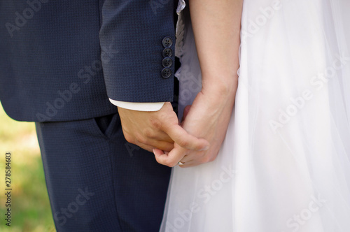 The hands of the bride and groom. Hands in the lock. The groom holds the hand of the bride tightly. Wedding day