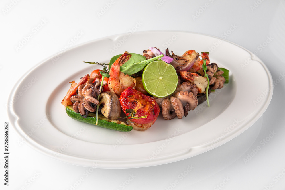 Luxurious seafood salad with shrimp, octopus, squid, fish, lime, cherry tomatoes, grilled vegetables and greens Banquet festive dishes. Fine dining restaurant menu. White background. Luxurious seafood salad with shrimp, octopus, squid, fish, lime, cherry tomatoes, grilled vegetables and greens Banquet festive dishes. Fine dining restaurant menu. White background.