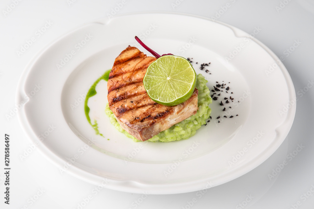 Grilled fish fillet salmon. Selected pieces of red fish with champagne and spinach risotto. Seafood. Banquet festive dishes. Fine dining restaurant menu. White background. Grilled fish fillet salmon. Selected pieces of red fish with champagne and spinach risotto. Seafood. Banquet festive dishes. Fine dining restaurant menu. White background.