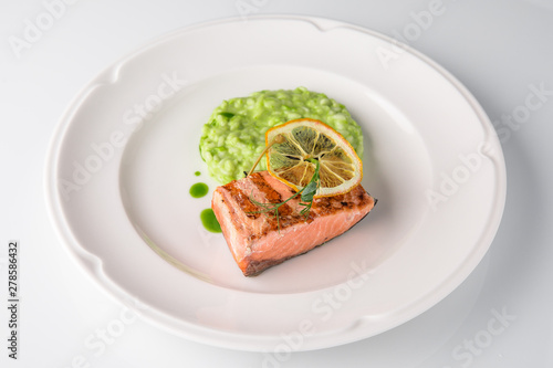 Grilled fish fillet salmon. Selected pieces of red fish with champagne and spinach risotto. Seafood. Banquet festive dishes. Fine dining restaurant menu. White background.