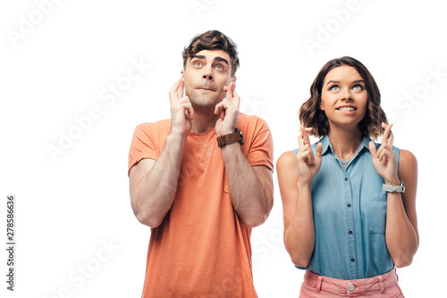 young man and woman looking up while holding crossed fingers isolated on white