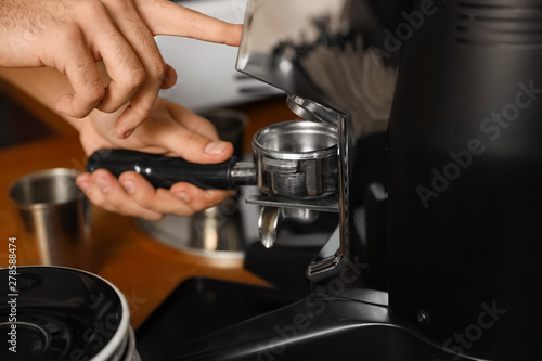 Barista pouring milled coffee from grinding machine into portafilter, closeup © New Africa
