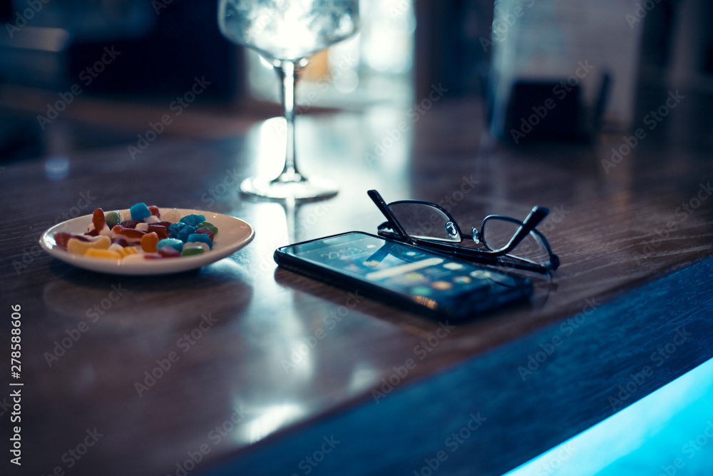 glasses and smartphone in a bar at night
