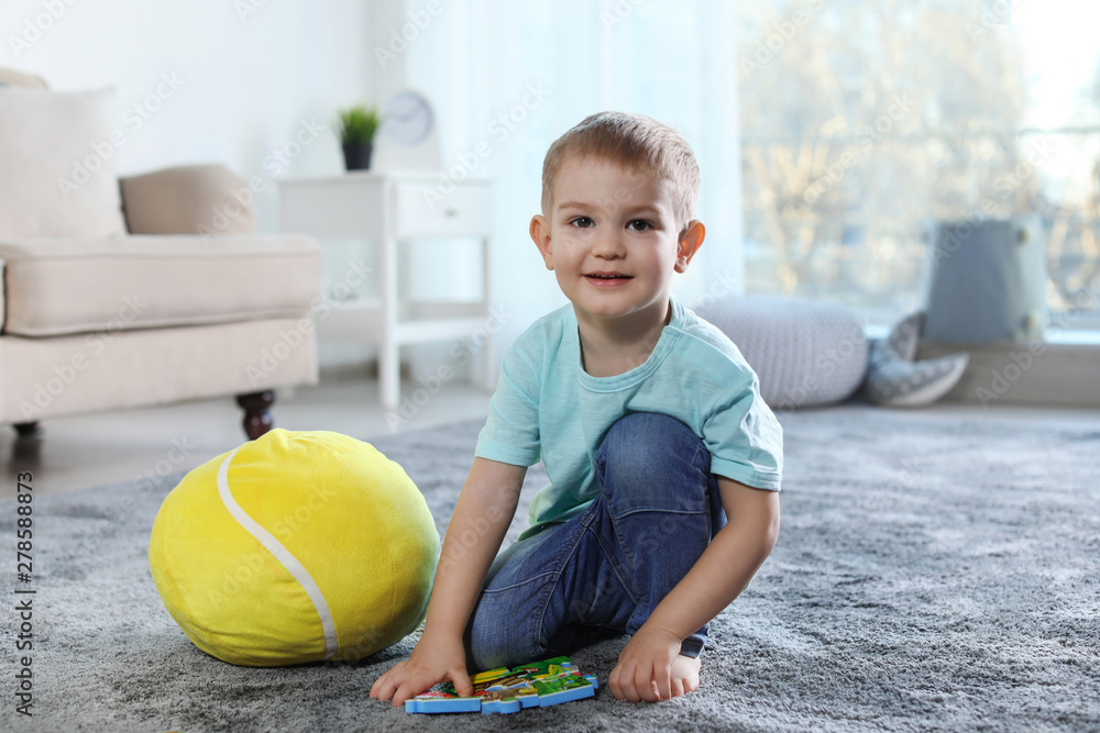 Fototapeta premium Cute child playing with soft toy on floor indoors