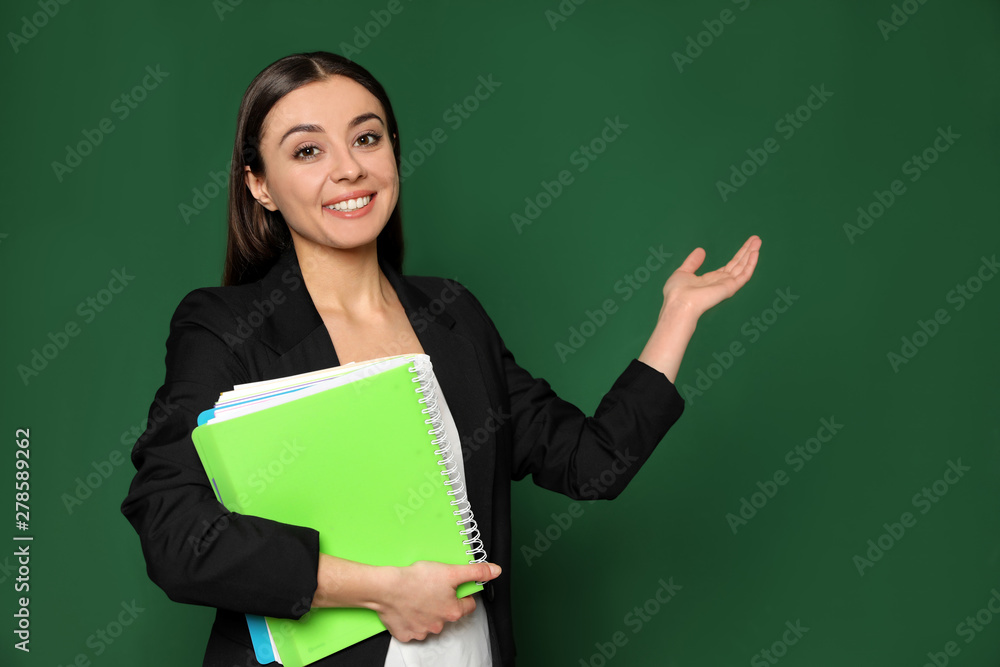 Portrait of young teacher with notebooks on green background Portrait of young teacher with notebooks on green background