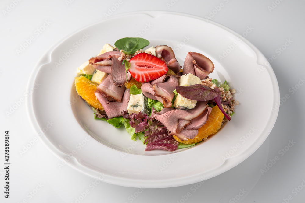 Salad of ham, prosciutto, pork or beef with vegetables, greens, berries and sauce. Nutritious, healthy dish. Banquet festive dishes. Gourmet restaurant menu. White background. Salad of ham, prosciutto, pork or beef with vegetables, greens, berries and sauce. Nutritious, healthy dish. Banquet festive dishes. Gourmet restaurant menu. White background.
