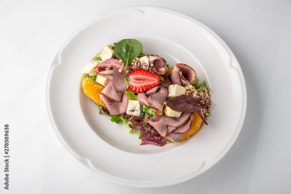 Salad of ham, prosciutto, pork or beef with vegetables, greens, berries and sauce. Nutritious, healthy dish. Banquet festive dishes. Gourmet restaurant menu. White background. Salad of ham, prosciutto, pork or beef with vegetables, greens, berries and sauce. Nutritious, healthy dish. Banquet festive dishes. Gourmet restaurant menu. White background.