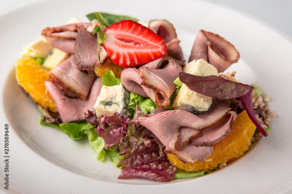 Salad of ham, prosciutto, pork or beef with vegetables, greens, berries and sauce. Nutritious, healthy dish. Banquet festive dishes. Gourmet restaurant menu. White background.