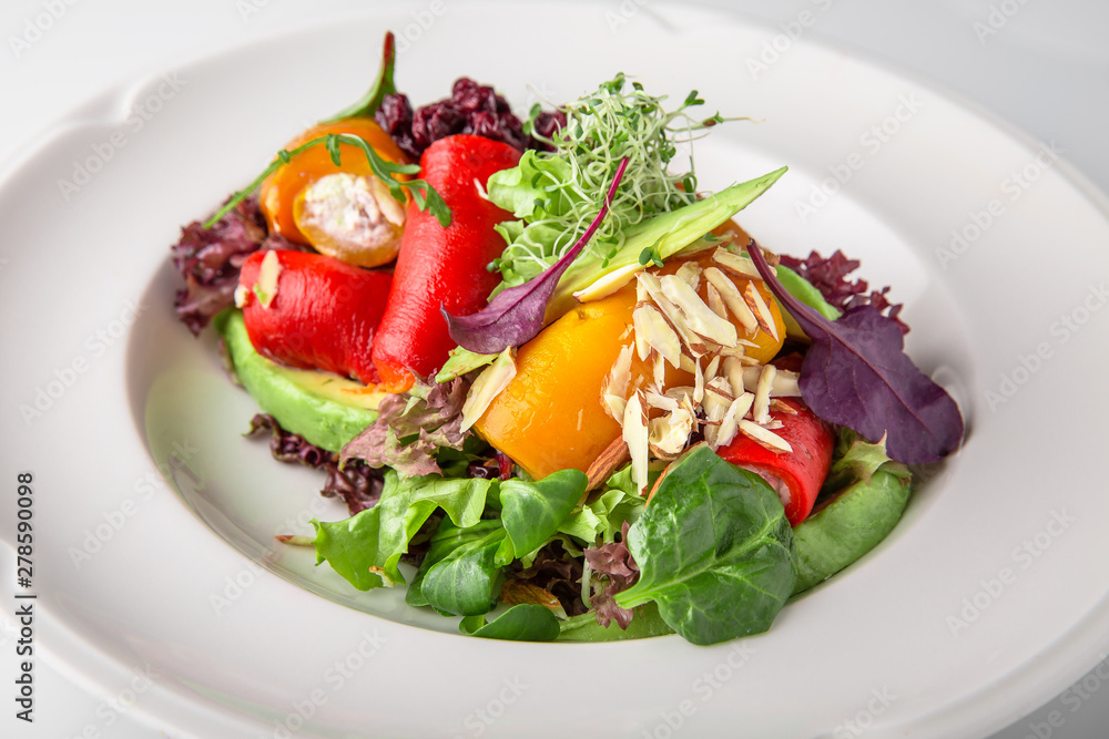 Salad of grilled vegetables in combination with fresh vegetables, cheese and sprouts of micro greens. Nutritious healthy dish. Banquet festive dishes. Gourmet restaurant menu. White background.