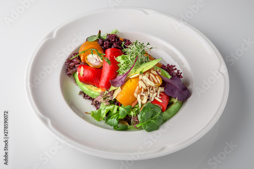 Salad of grilled vegetables in combination with fresh vegetables, cheese and sprouts of micro greens. Nutritious healthy dish. Banquet festive dishes. Gourmet restaurant menu. White background.