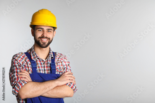 Murais de parede Portrait of construction worker in uniform on light background, space for text