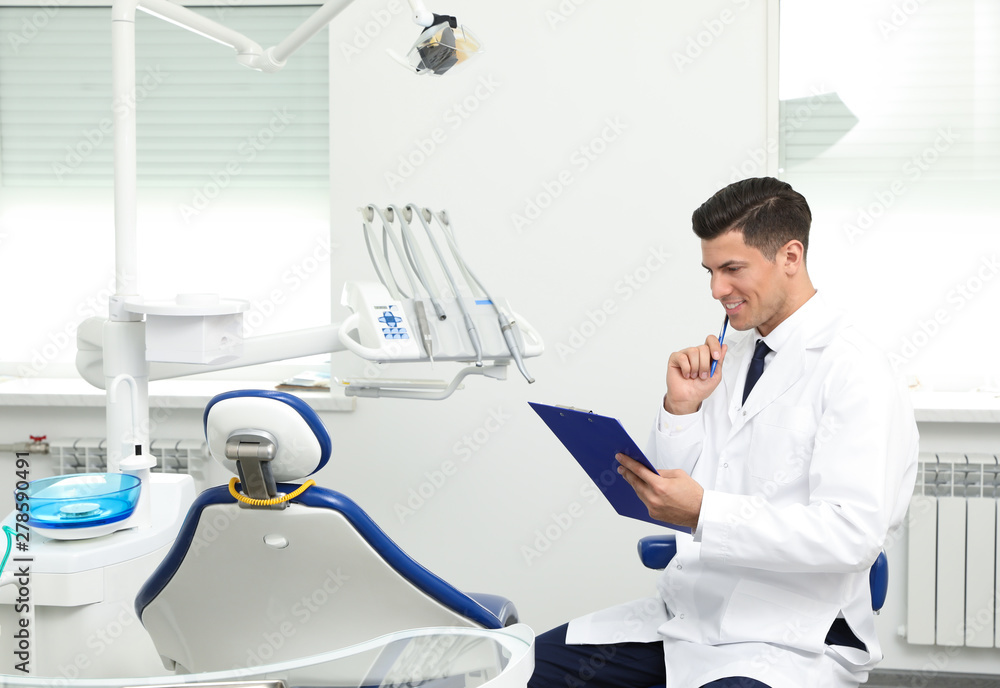 Portrait of professional male dentist with clipboard in clinic. Space for text Portrait of professional male dentist with clipboard in clinic. Space for text