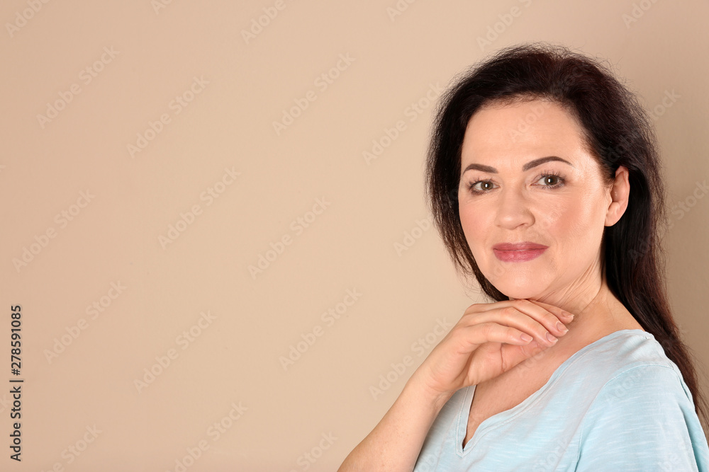 Portrait of charming mature woman with healthy beautiful face skin and natural makeup on beige background, space for text Portrait of charming mature woman with healthy beautiful face skin and natural makeup on beige background, space for text