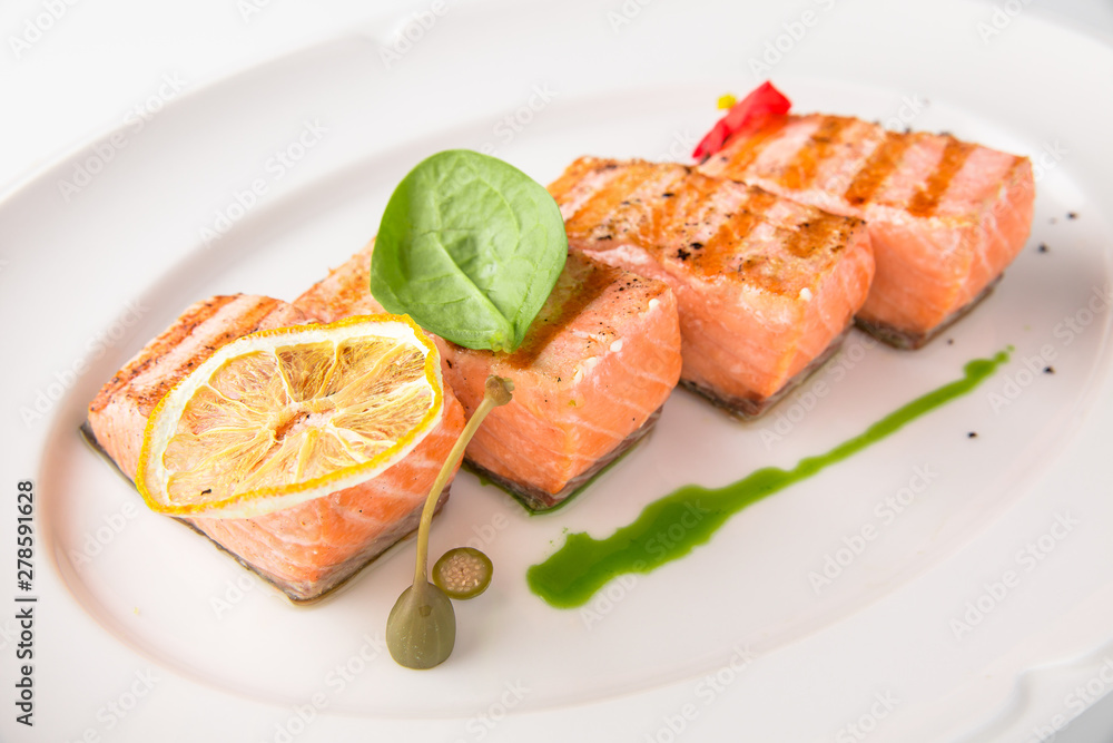 Grilled salmon fish fillet (red fish). Seafood. Banquet festive dishes. Fine dining restaurant menu. White background. Grilled salmon fish fillet (red fish). Seafood. Banquet festive dishes. Fine dining restaurant menu. White background.