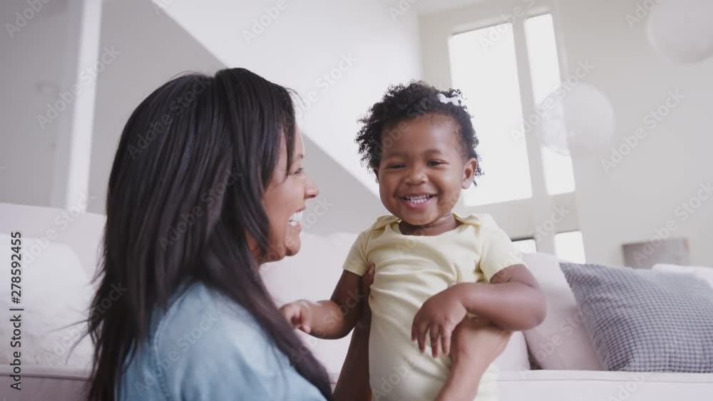 Mother Playing With Baby Daughter Tickling Her And Lifting Her In The Air At Home Mother Playing With Baby Daughter Tickling Her And Lifting Her In The Air At Home