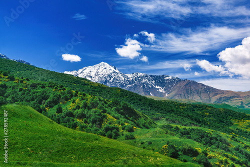 Beautiful view of alpine meadows in the Caucasus mountains. Pastures, meadows on the slopes and snow-capped mountains.