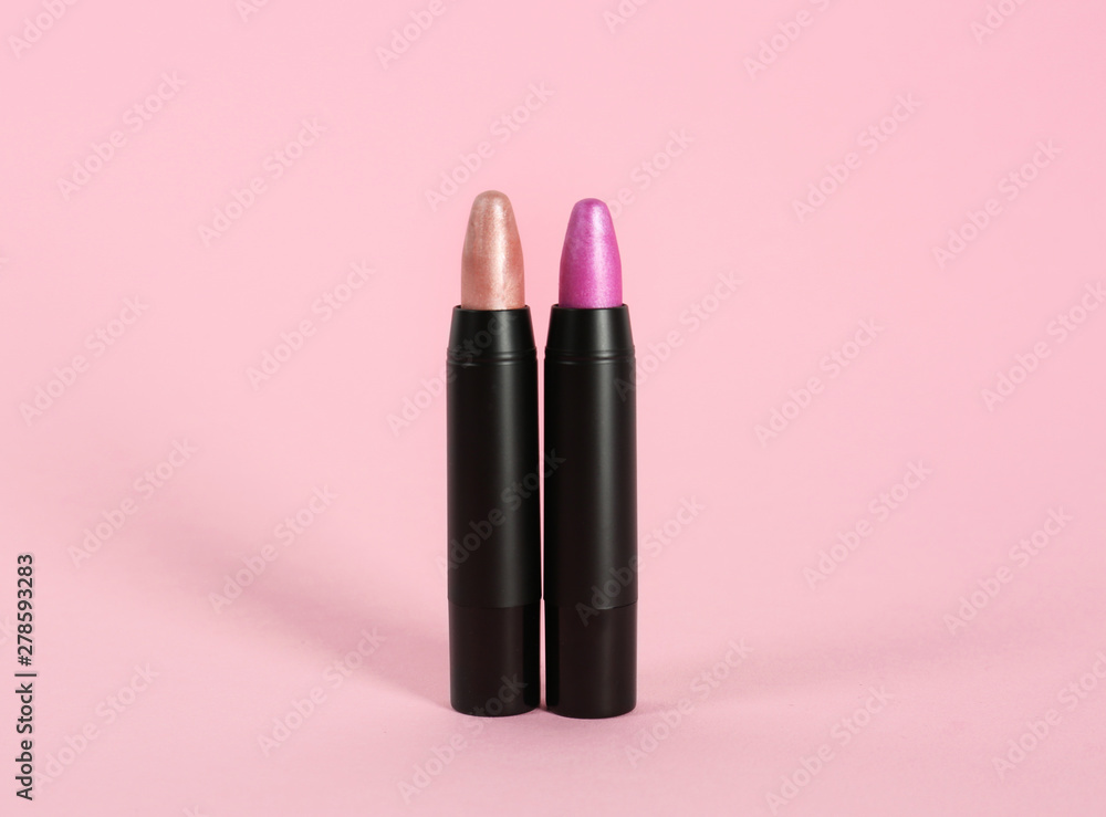 Obraz premium Bright lipsticks in black tubes on pink background