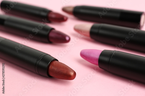 Set of bright lipsticks in black tubes on pink background