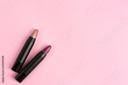 Bright lipsticks in black tubes on pink background, flat lay. Space for text