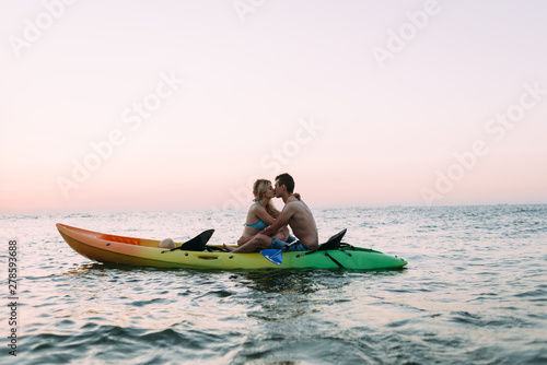 dawn on the ocean, a loving couple kayaking and kissing © mtrlin