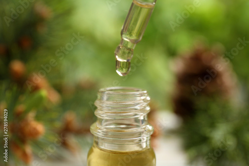 Pipette and bottle of essential oil on blurred background, closeup