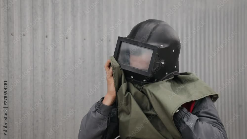 Industrial Engineer Wearing Protective Clothing Puts on Hard Hat. Factory worker putting his hard hat and overalls. Sandblasting uniform Industrial Engineer Wearing Protective Clothing Puts on Hard Hat. Factory worker putting his hard hat and overalls. Sandblasting uniform