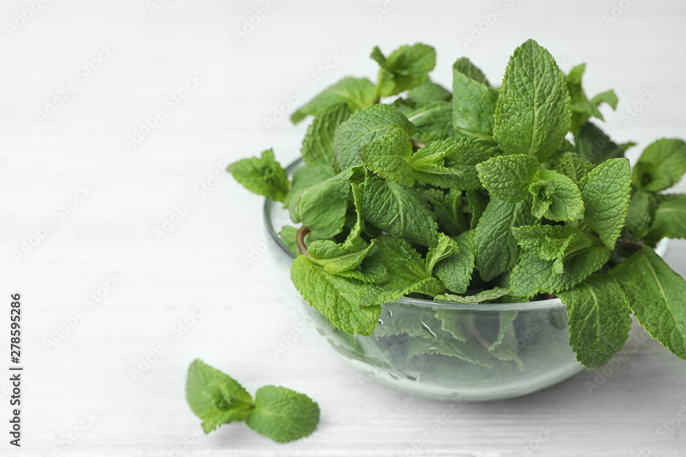 Glass bowl with fresh green mint on table. Space for text Glass bowl with fresh green mint on table. Space for text
