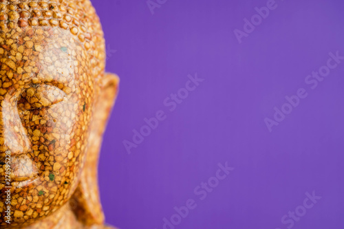 Buddha stone sculpture close-up purple background macro