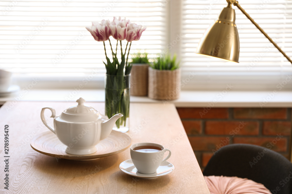 Fototapeta premium Tea set on table near window with blinds indoors