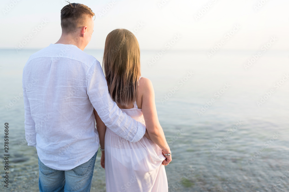 Beach couple looking at ocean view from behind. Relaxing on summer travel vacations in tropical destination Beach couple looking at ocean view from behind. Relaxing on summer travel vacations in tropical destination