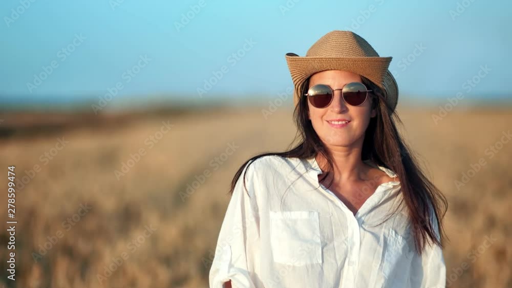 Smiling cowboy travel female posing surrounded by wheat field playing with hair looking at camera Smiling cowboy travel female posing surrounded by wheat field playing with hair looking at camera
