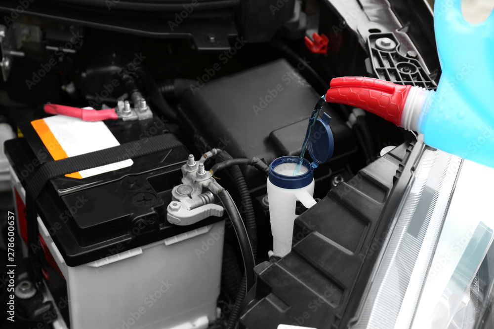 Pouring liquid from plastic canister into car washer fluid reservoir, closeup Pouring liquid from plastic canister into car washer fluid reservoir, closeup