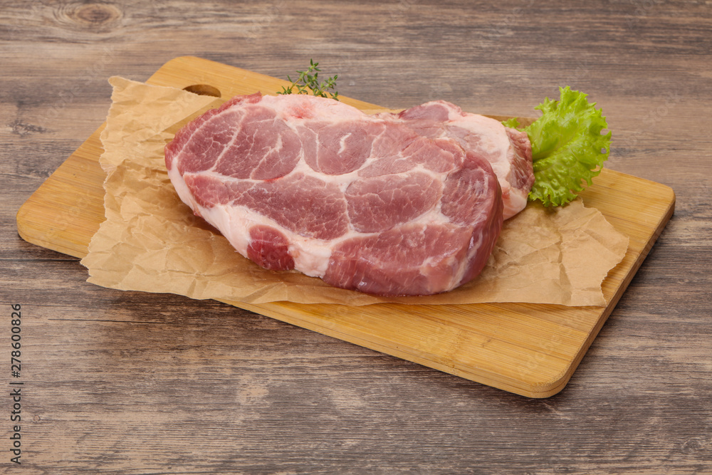 Raw pork steak over wooden board Raw pork steak over wooden board