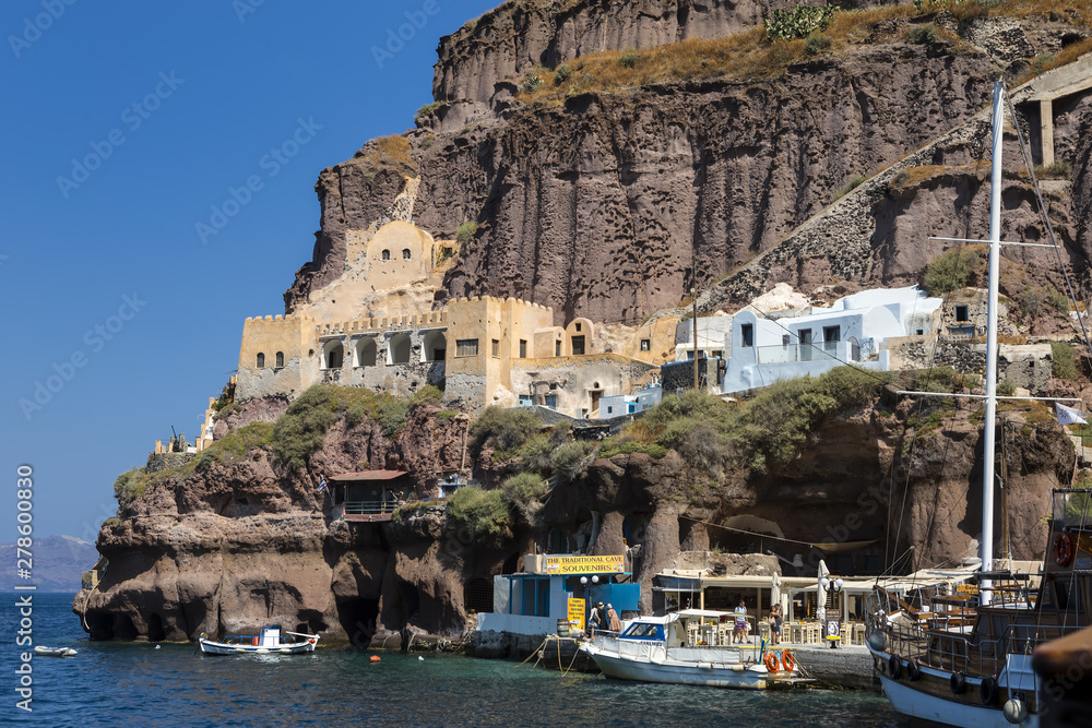 FIRA, GREECE - JUNE 16, 2019: Beautiful view of the Old Port in Fira town with the sailboat  ship in the foreground, Santorini, Greece,